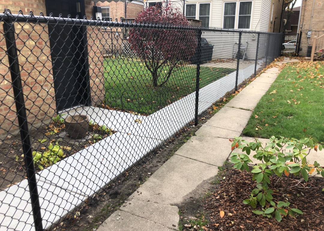 Custom black chain-link fence installation in residential backyard in Carson, CA